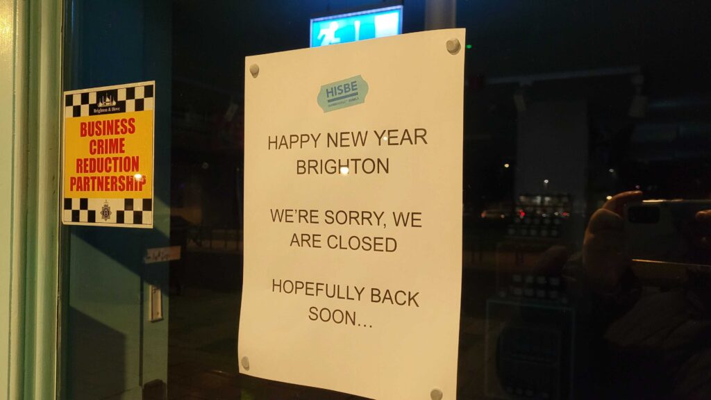 A sign on doors of grocery shop saying "Happy new year Brighton. We're sorry, we are closed. Hopefully back soon."